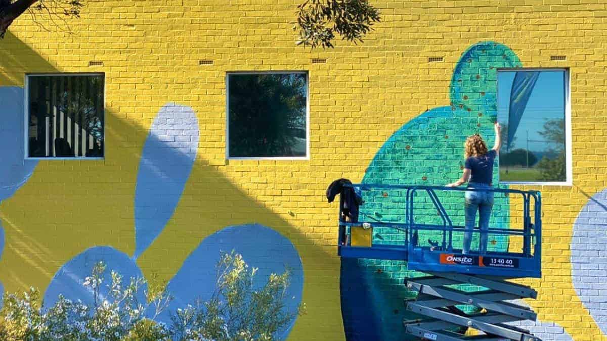 Perth-based mural artist, Susan Respinger painting an artwork on a scissor lift.